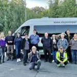 Brandholzer Team vor dem RMD-Bus. Ein dutzend Menschen teilweise in Arbeitskleidung strahlen in die Kamera